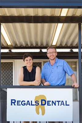 Two People Standing Behind Regals Dental Sign - Preventative Dentistry